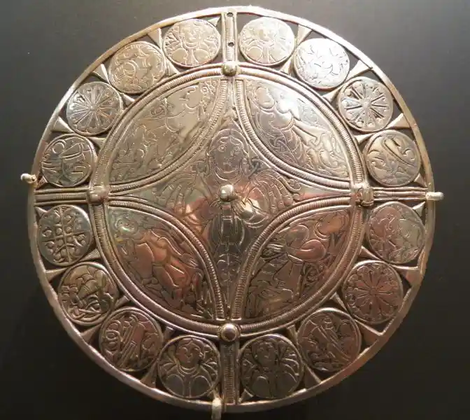 An angel, a cross and solar disc on a brooch